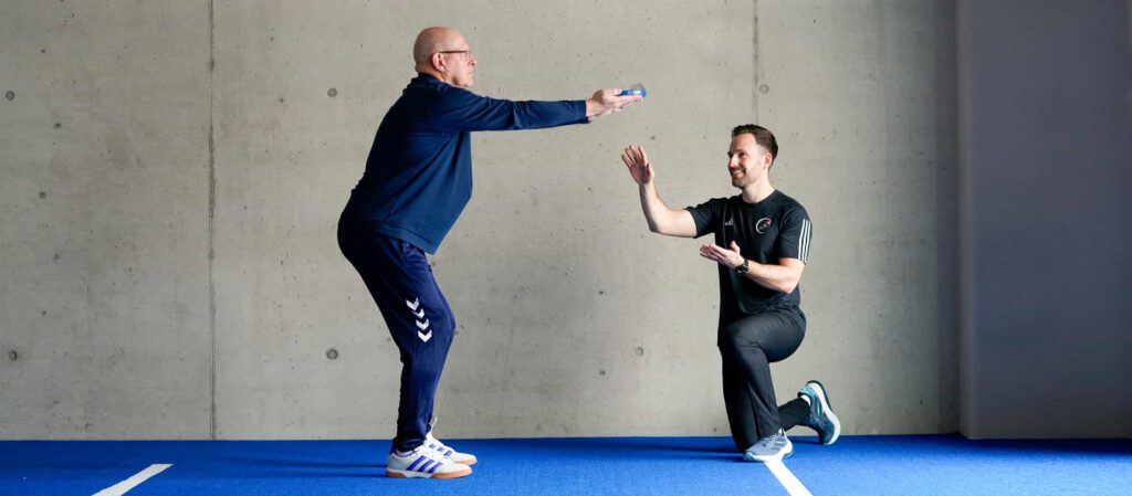 Coach Timm zeigt einem Kunden eine gezielte Rückenübung zur Verbesserung der Belastbarkeit und zur Reduktion von Rückenschmerzen im Trainingsalltag.