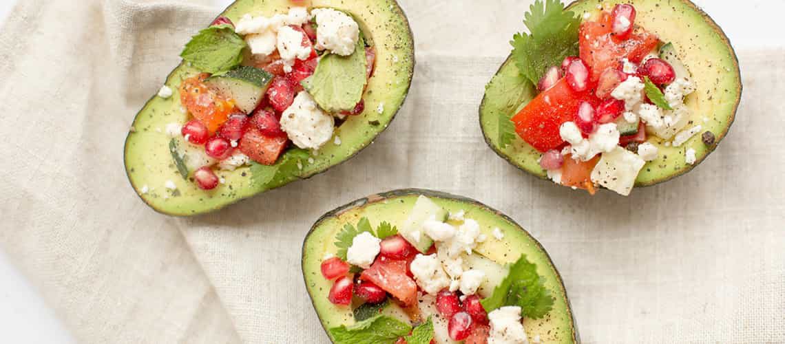 Gefüllte Avocado-Hälften mit Tomaten, Feta, Minze und Granatapfelkernen – gesunde Fette und Antioxidantien für die Ernährung zur Unterstützung der Heilung bei Verletzungen.